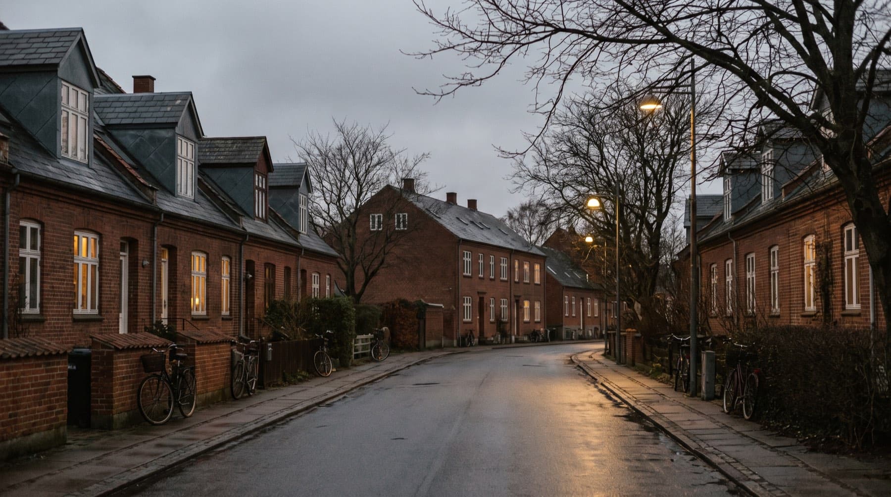 Dansk villavej i skumringen med lys i vinduerne